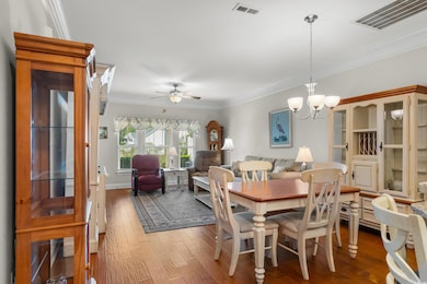 Dining space with ornamental molding, wood finished floors, a chandelier, and a ceiling fan
