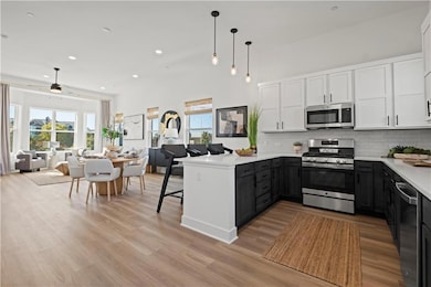 Kitchen featuring light hardwood / wood-style floors, kitchen peninsula, stainless steel appliances, and a wealth of natural light