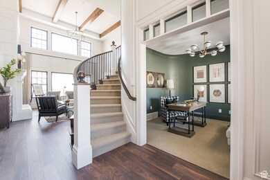 Staircase featuring hardwood / wood-style flooring, a towering ceiling, a chandelier, and beam ceiling