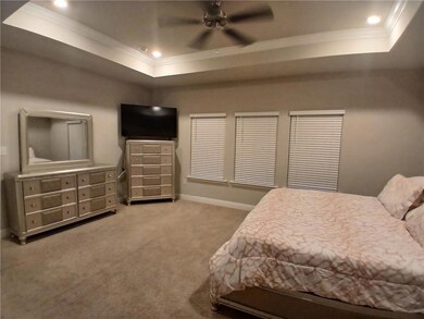 Bedroom featuring crown molding, a tray ceiling, carpet floors, a ceiling fan, and recessed lighting