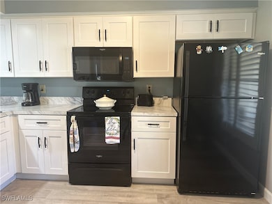Kitchen featuring black appliances, white cabinets