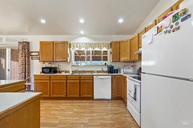 Kitchen featuring white appliances, brown cabinets, light countertops, and recessed lighting
