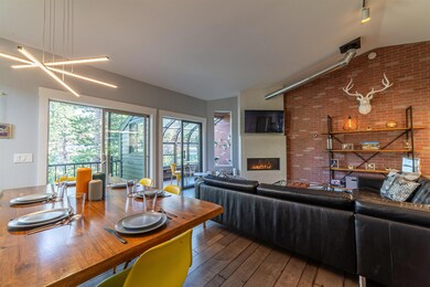 Living room with vaulted ceiling, wood-type flooring, and a glass covered fireplace