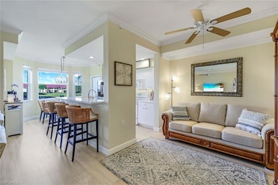Living area with baseboards, light wood-type flooring, ornamental molding, and a ceiling fan