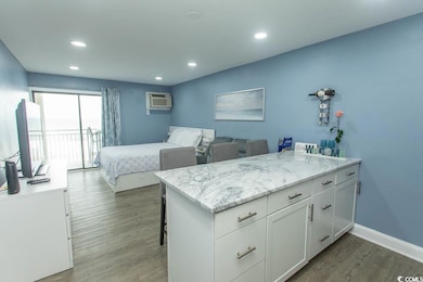 Bedroom featuring wood finished floors, a wall unit AC, recessed lighting, and access to exterior