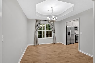 Dining room features tray ceiling and view to kitchen.