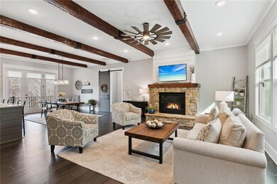 Living room featuring beam ceiling, a stone firepl