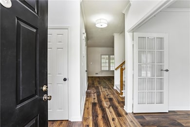 Foyer entrance featuring ornamental molding, stairs, wood finished floors, baseboards, and a textured ceiling