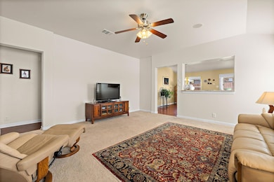 Carpeted living area with baseboards and a ceiling fan