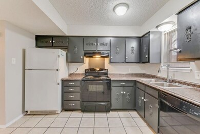 Kitchen with black appliances, a textured ceiling, gray cabinets, light tile patterned floors, and under cabinet range hood