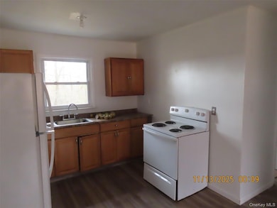 Kitchen featuring white appliances, brown cabinetry, and dark wood-style flooring
