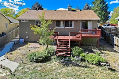 Rear view of property with a fenced backyard, a wooden deck, a chimney, roof with shingles, and stairway