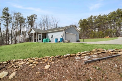 Rear view of property featuring a garage, a yard, 