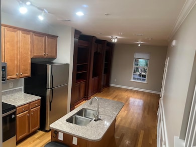 Kitchen with a sink, appliances with stainless steel finishes, light wood-style flooring, brown cabinets, and crown molding