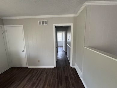 Hall with wood finished floors, ornamental molding, and a textured ceiling