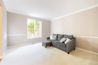 Sitting room with ornamental molding and light carpet