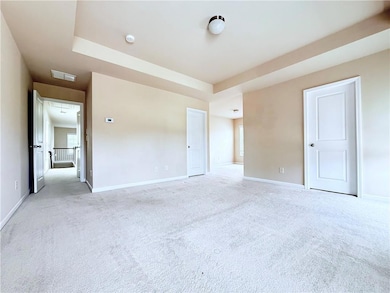 Unfurnished bedroom featuring attic access and light carpet