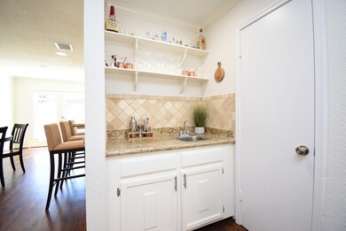 Wet bar has granite counters and shelves