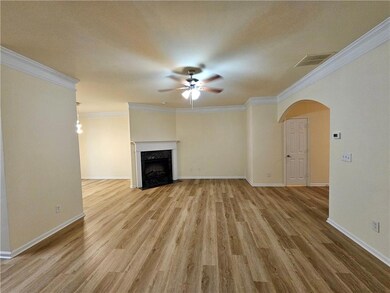 Unfurnished living room featuring a ceiling fan, arched walkways, light wood-type flooring, ornamental molding, and a premium fireplace
