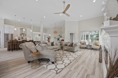 Living area featuring a high ceiling, recessed lighting, light wood-style flooring, ceiling fan, and ornamental molding