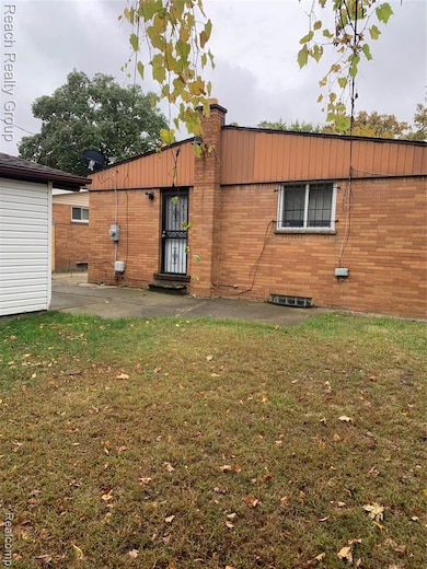 Rear view of property with a lawn, a chimney, brick siding, and a patio area