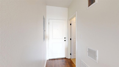 Hall with dark wood-style floors and visible vents