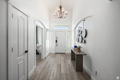 Foyer entrance featuring high vaulted ceiling, light wood-style floors, and a chandelier