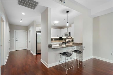 Kitchen featuring appliances with stainless steel finishes, dark wood finished floors, backsplash, white cabinetry, and recessed lighting