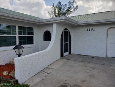 Doorway to property featuring metal roof, a standing seam roof, an attached garage, and stucco siding