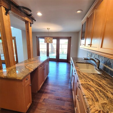 Kitchen with a kitchen island, dark wood-style floors, recessed lighting, dark stone countertops, and glass insert cabinets