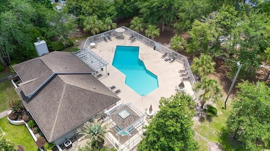 View of subject property featuring a pool and a tree filled landscape