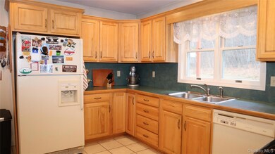 Kitchen featuring white appliances, light tile patterned floors, dark countertops, and decorative backsplash