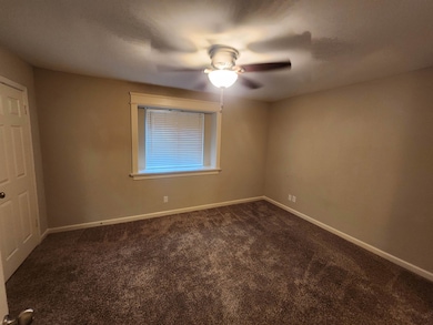 Unfurnished room with baseboards, dark carpet, and