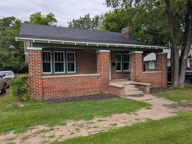 View of front of home with brick siding, a chimney, and a front yard