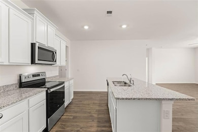 Kitchen featuring an island with sink, sink, white