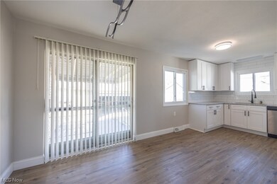 Kitchen featuring sink, stainless steel dishwasher, backsplash, wood-type flooring, and white cabinets