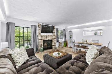 Living area with plenty of natural light, arched walkways, a textured ceiling, a fireplace, and wood finished floors