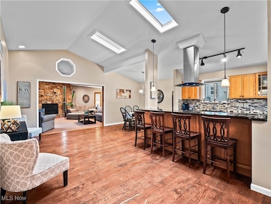 Kitchen with a skylight, a kitchen breakfast bar, lofted ceiling, decorative light fixtures, and backsplash