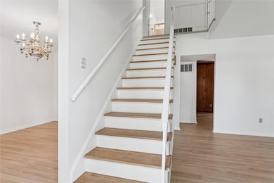 Staircase with wood finished floors and a chandelier