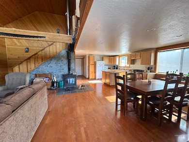 Dining room featuring lofted ceiling, a wood stove, wood finished floors, and wood walls