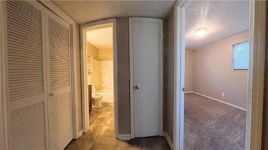 Hall with a textured ceiling, tile patterned flooring, and carpet flooring
