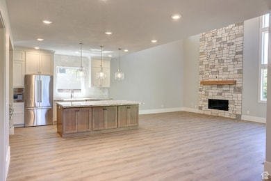 Kitchen featuring freestanding refrigerator, light wood-style flooring, decorative backsplash, a center island, and open floor plan