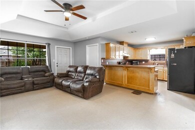 Living room with sink, ceiling fan, light tile floors, and a raised ceiling