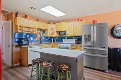 Open concept kitchen featuring natural gas range/oven, Spanish-style tiled back splash, well maintained hard surface counter tops, lots of storage, a kitchen island and breakfast counter, a dishwasher and stainless steel sink