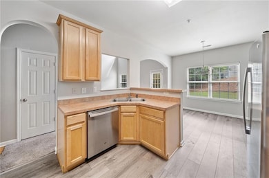 Kitchen featuring stainless steel appliances, light brown cabinets, a sink, and light wood-style floors