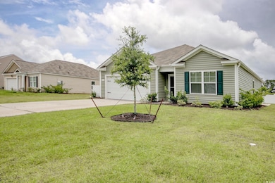 Single story home with driveway, an attached garage, and a front lawn