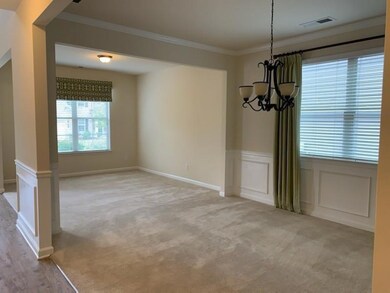 Unfurnished dining area with a chandelier, ornamental molding, light carpet, a wainscoted wall, and a decorative wall