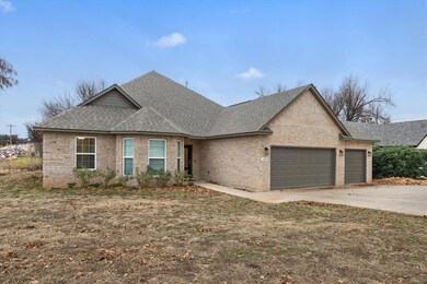View of front of property featuring roof with shingles, an attached garage, and brick siding