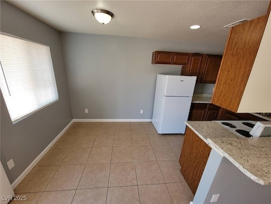 Kitchen with freestanding refrigerator, light tile