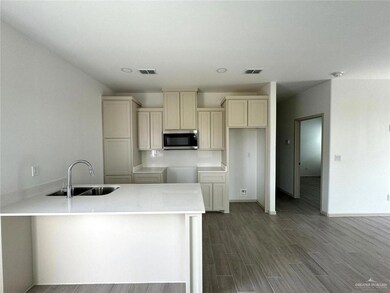 Kitchen with dark wood finished floors, stainless steel microwave, visible vents, and a sink
